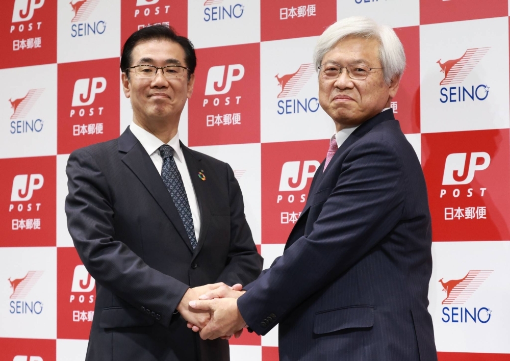 Japan Post CEO Tetsuya Senda (right) and his Seino Transportation counterpart Satoshi Takahashi announce their companies' agreement on joint long-haul truck operations, in Tokyo on Thursday.