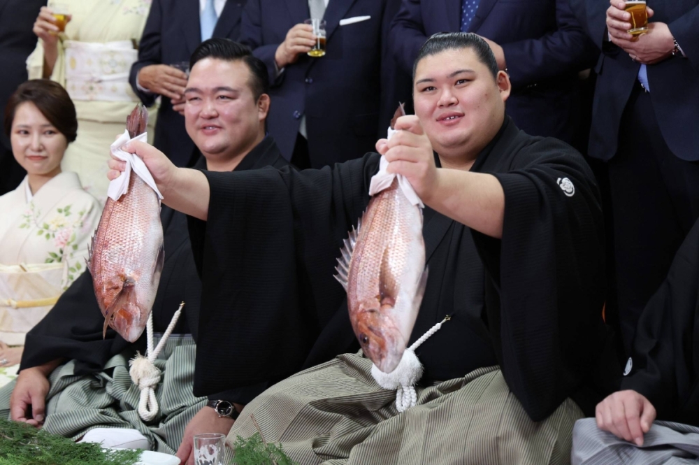 Newly minted ozeki Onosato holds up two fish during his promotion ceremony in Ami, Ibaraki Prefecture, on Wednesday. Newly minted ozeki Onosato holds up two fish during his promotion ceremony in Ami, Ibaraki Prefecture, on Wednesday.