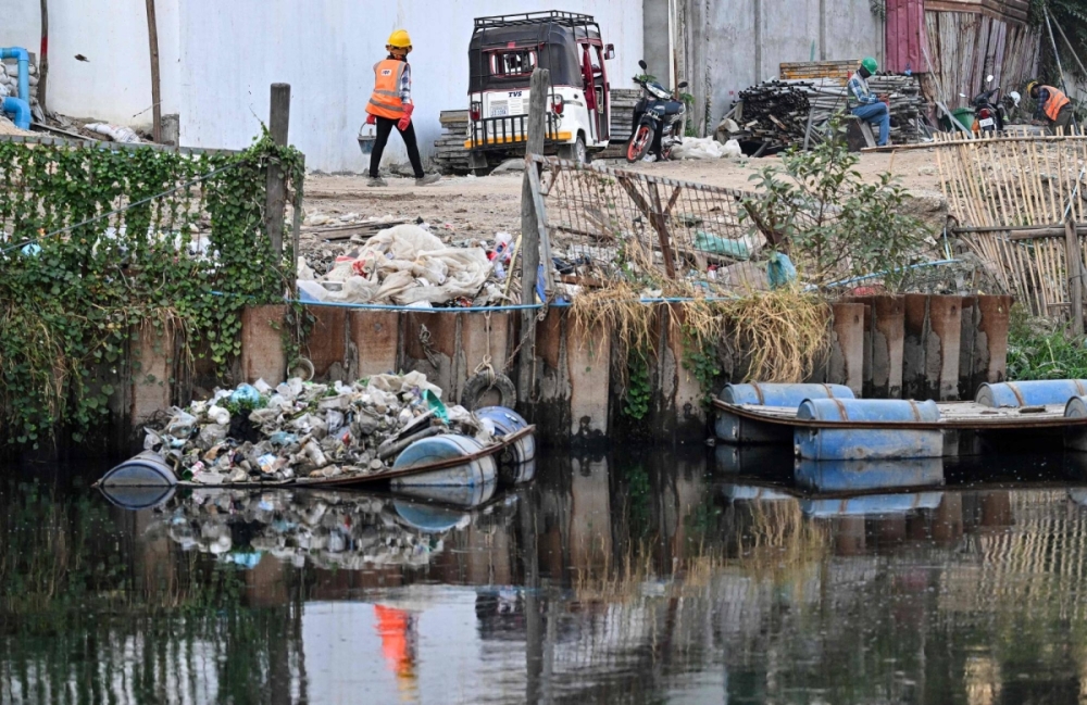 A worker walks next to a pile of plastic waste on a platform in a canal in Phnom Penh on Jan. 31. A worker walks next to a pile of plastic waste on a platform in a canal in Phnom Penh on Jan. 31.