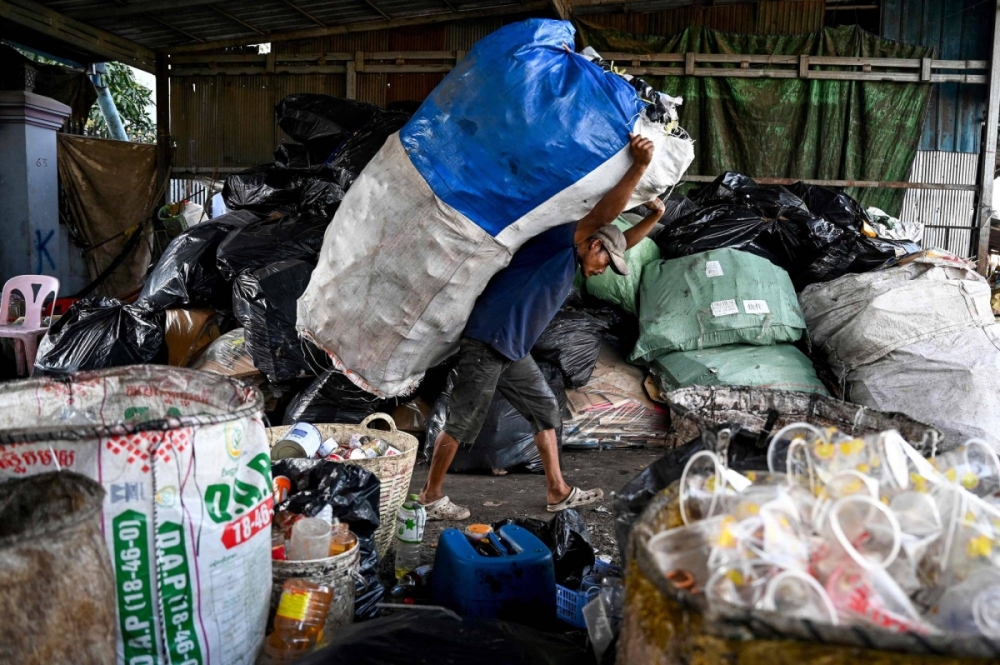 A worker carries a bag containing plastic bottles at a recycling depot on the outskirts of Phnom Penh on Jan. 30. A worker carries a bag containing plastic bottles at a recycling depot on the outskirts of Phnom Penh on Jan. 30.