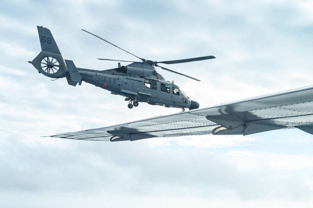 A Chinese People's Liberation Army Navy helicopter is seen from aboard a Philippine Bureau of Fisheries and Aquatic Resources (BFAR) aircraft in the skies above Scarborough Shoal in the disputed South China Sea on Feb. 18.
