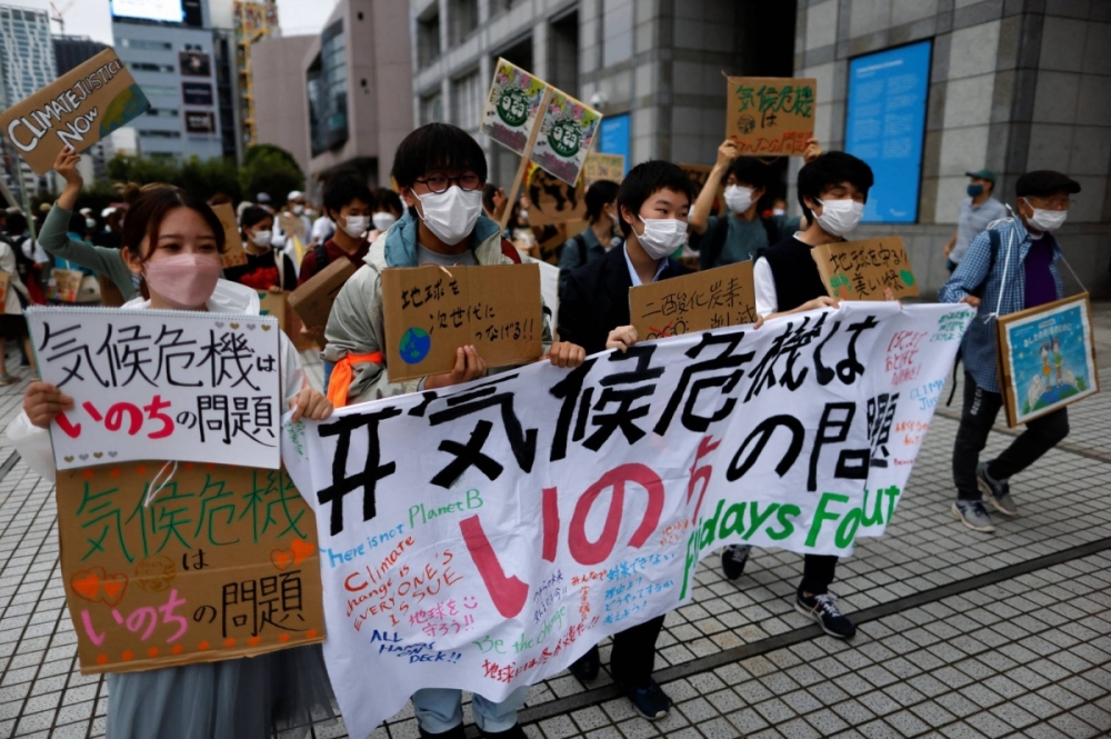 People raise placards and hold a banner as they take part in a global climate protest, next to the United Nations University in Tokyo in September 2022. People raise placards and hold a banner as they take part in a global climate protest, next to the United Nations University in Tokyo in September 2022.