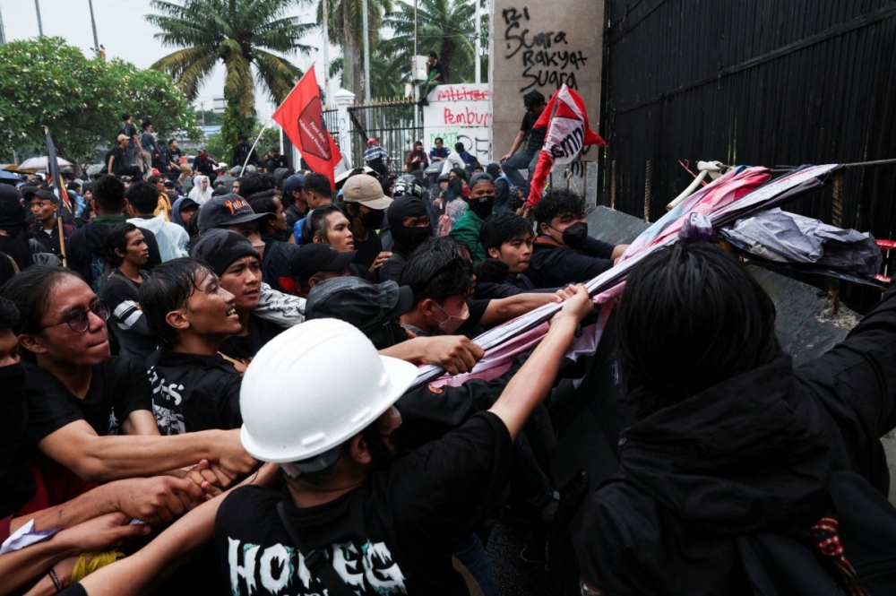 Des manifestants tentant d'arracher les grilles du parlement en tirant sur des lambeaux de tissus