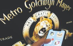DONE DEAL This file illustration photo taken May 26, 2021 shows the Amazon logo on a smartphone in front of the MGM lion on a computer screen in Los Angeles. Amazon has closed its $8.45-billion deal to buy the storied MGM studios, the online giant said on Thursday, March 17, 2022, boosting its streaming ambitions with a catalog including the James Bond and Rocky film franchises. Amazon’s dominance in online retailing has drawn anti-monopoly scrutiny, but this buyout won approval from EU authorities on March 15, while US regulators have not blocked the agreement originally announced in May 2021. AFP PHOTO
