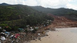 An aerial view shows destroyed houses on a collapsed mountain side along the coastline in the village of Pilar, Abuyog town, Leyte province on April 14, 2022 day after a landslide struck the village due to heavy rains at the height of tropical Storm Megi. (Photo by Bobbie ALOTA / AFP)