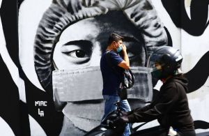 A man wearing a mask walks past a mural in Paco, Manila, on 14 May 2022. PHOTO by MIKE ALQUINTO