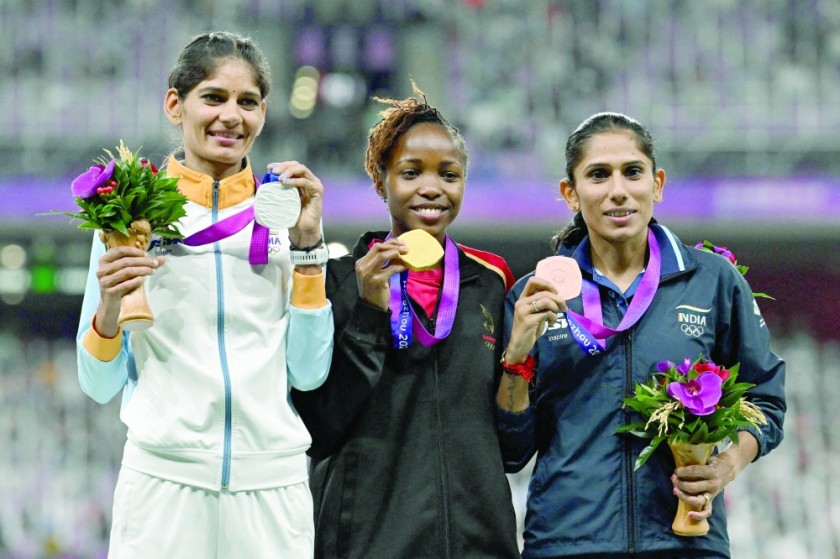 (Left) Women's 3000m steeplechase silver medalist Parul Chaudhary of India, gold medalist Winfred Yavi of Bahrain and bronze medalist Priti of India celebrate on the podium. -AFP