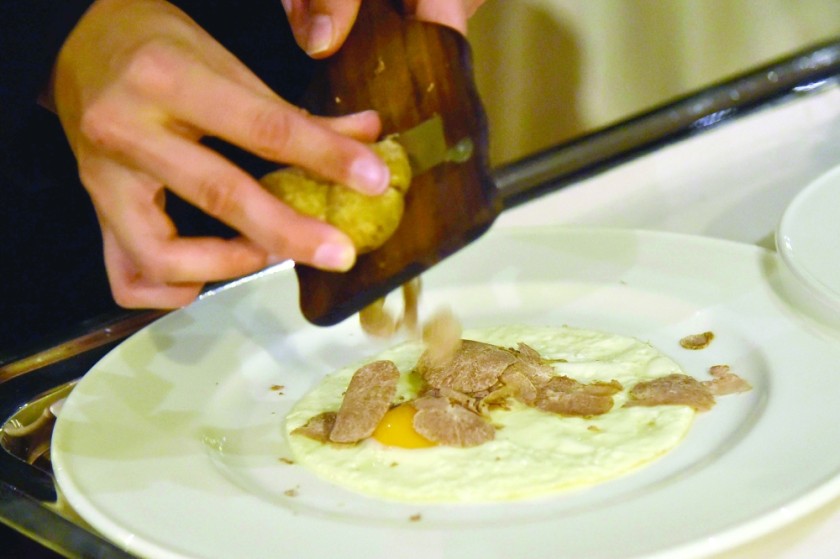A waiter grates truffle on an egg. — AFP